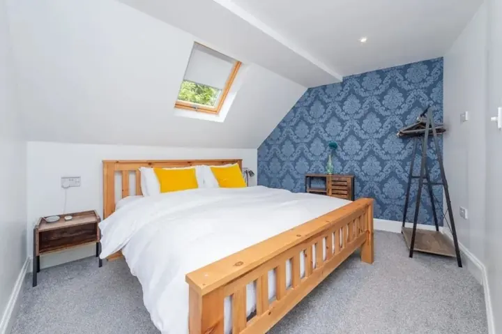 Main bedroom with a wooden bed and patterned feature wall