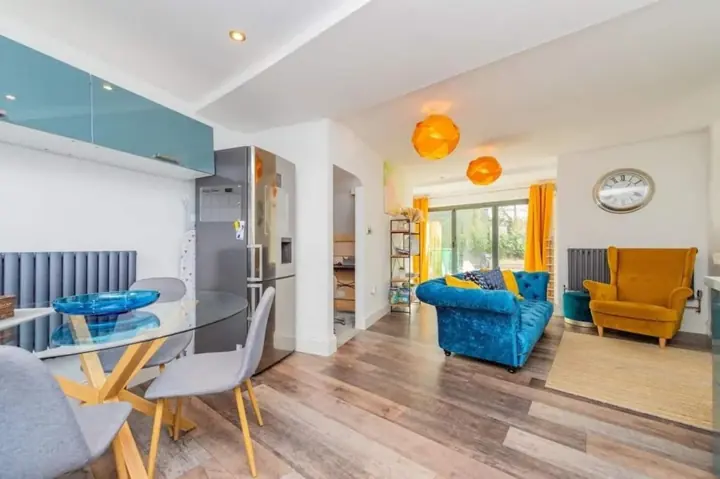 Glass dining table with chairs, looking through to the lounge